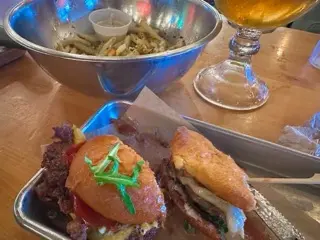 Photo of two wagyu burgers, truffle parm fries, and a rose blonde beer