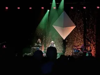 Photo of Kaleo performing beneath green spotlights and a large suspended diamond-shaped set piece at The Pinnacle in Nashville