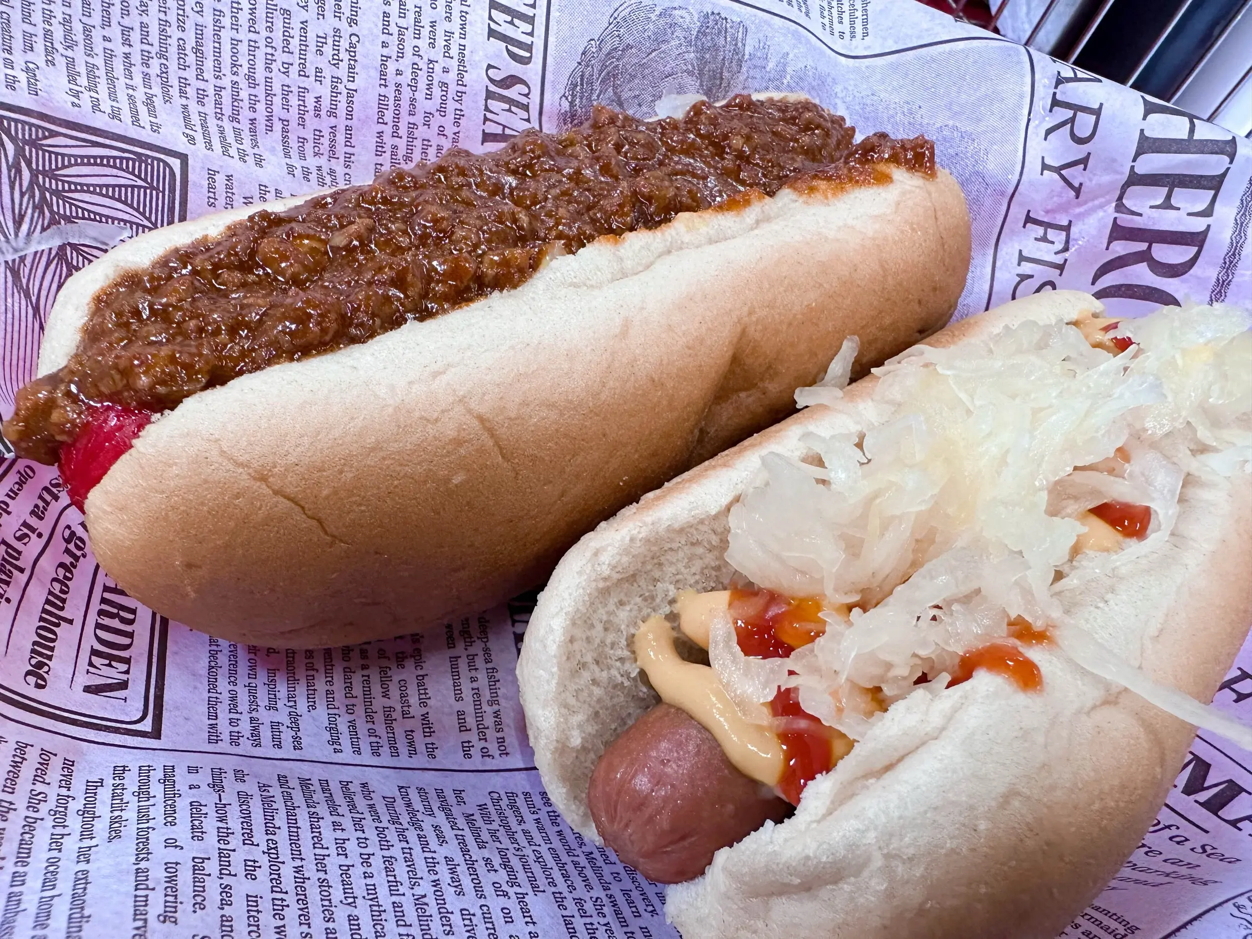 Two hot dogs from Skeeter's in Wytheville on branded paper, one covered in dark chili and one topped with kraut, mustard, and ketchup